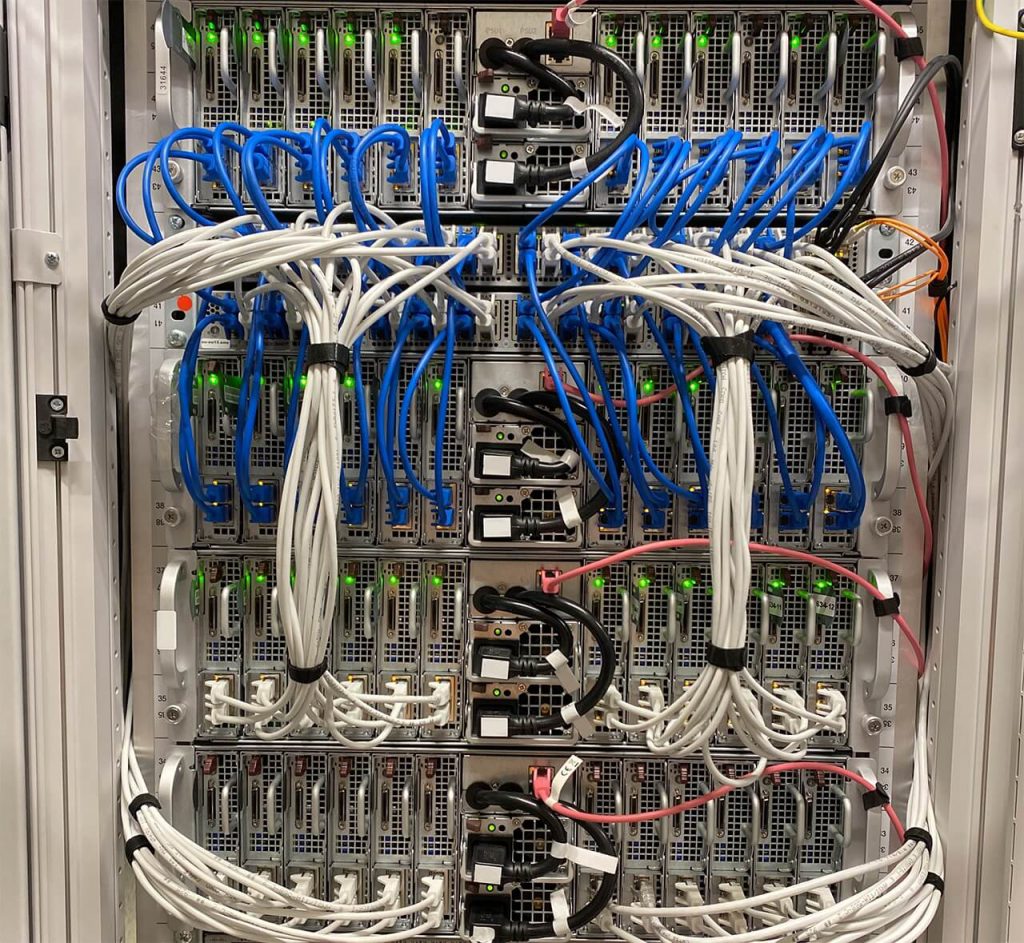 Server rack with multiple servers connected by blue and white cables. Green indicator lights are visible on the servers.